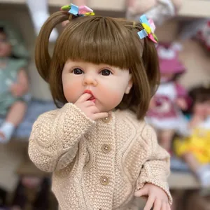 Lifelike 55cm reborn baby doll with pigtails wearing a cream knitted cardigan