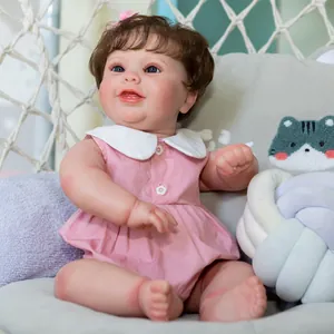 Lifelike 50cm newborn baby doll with brown curls sitting in a white woven chair