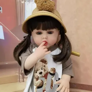 Lifelike 55cm reborn baby doll with brown pigtails wearing a straw hat and bear t-shirt