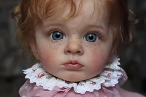 Close-up of lifelike reborn doll featuring hand-painted freckles and curly hair details