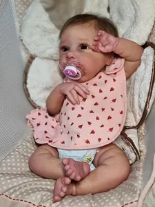 Detailed view of lifelike reborn baby doll with ladybug bib, diaper, and pink pacifier