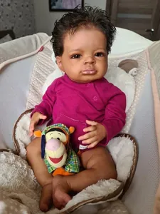 Gros plan d'une poupée reborn noire réaliste avec cheveux bouclés dans son berceau