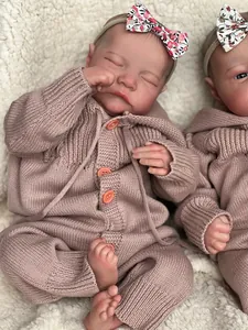 Close-up of reborn baby doll sleeping in pink knit romper with floral headband