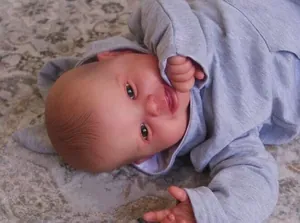 Gros plan d'une poupée reborn réaliste avec texture de peau et sweat à capuche gris