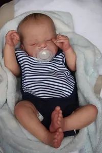 Close-up of sleeping reborn baby doll Sam with blue striped outfit and pacifier