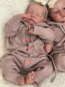 Macro shot of twin reborn baby dolls wearing pink knit rompers on white fleece