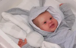 Détail d'une poupée Reborn 60cm en sweat à capuche lapin gris et lapin en peluche