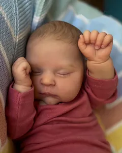 Close-up of sleeping reborn baby doll with 3D hand-painted skin and pink knit romper