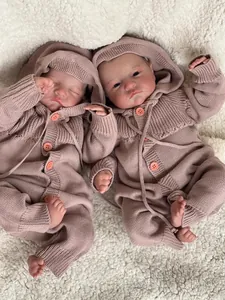 Detailed view of twin reborn baby dolls wearing pink knitted rompers on white plush rug