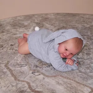 Poupée reborn réaliste de 60 cm en tenue de lapin gris avec de longues oreilles sur tapis