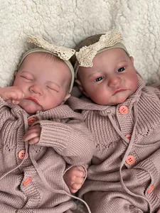 Detailed close-up of twin reborn dolls in pink cardigans on a soft white faux fur blanket