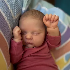 Realistic sleeping reborn baby doll in pink romper on a colorful knitted blanket