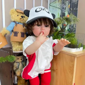 Muñeca bebé realista de 55 cm con gorro de panda y ropa deportiva roja en entorno hogareño