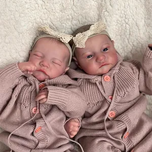 Realistic 49cm reborn twin dolls in pink knit jumpers lying on a white plush blanket