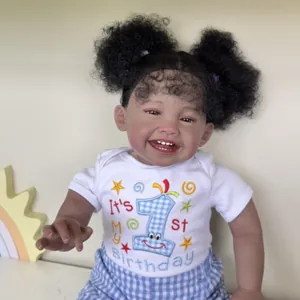Deep skin tone Mila reborn doll with black bun hair wearing 1st birthday outfit set