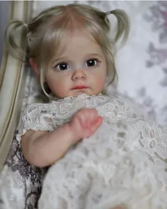Nahaufnahme der lebensechten Reborn-Puppe Maggi mit blonden Zöpfen und weißem Spitzenkleid