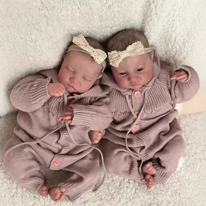 Realistic twin reborn baby dolls Levi in pink knit rompers lying on soft white wool blanket