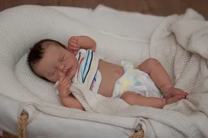 Macro shot of realistic sleeping reborn baby doll with lifelike skin and stripe vest
