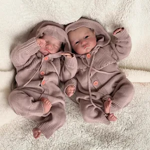 Realistic 49cm reborn twin baby dolls in soft pink knit rompers on a white plush blanket