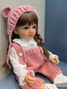 Détail d'une poupée reborn réaliste avec tresses brunes en tenue tricotée rose et dentelle