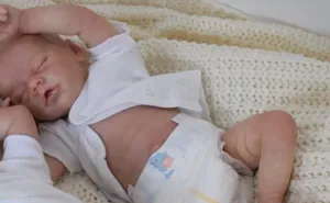 Gros plan d'une poupée reborn de 18 pouces endormie sur une couverture en tricot doux