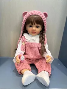 Détail d'une poupée Reborn de 55 cm avec bonnet d'ours rose et salopette à fleurs
