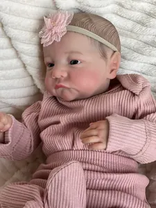 Close-up of 49cm reborn baby doll Levi in pink ribbed romper on white plush blanket