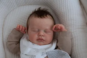 Close-up of lifelike newborn baby doll with soft skin texture and koala bib in sleeping pose