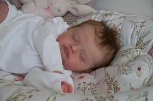 Close-up of sleeping Reborn Baby Doll with hand-rooted hair and plush bunny prop
