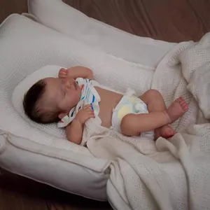 Lifelike Loulou reborn doll in soft white baby nest with striped outfit and blanket