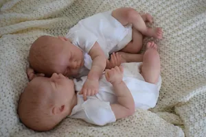 Détails de poupées reborn jumeaux endormis sur une couverture en tricot beige doux