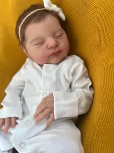 Close-up of 19 inch reborn doll with soft skin texture wearing white headband and romper