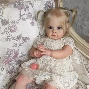 Reborn-Puppe Maggi mit blonden Zöpfen im Spitzenkleid auf einem floralen Sessel