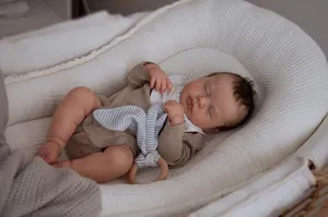 Detailed overhead view of a newborn baby sleeping in a white waffle fabric portable bassinet
