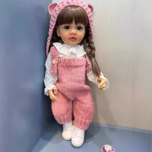 Poupée Reborn réaliste de 55cm en tenue tricotée rose et baskets blanches contre un mur