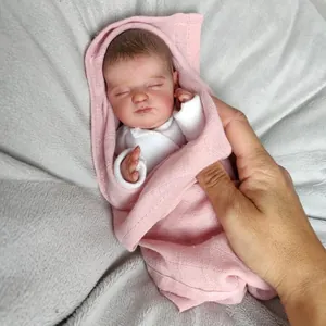 Lifelike mini 10-inch reborn baby doll sleeping in pink knitted wrap and white top