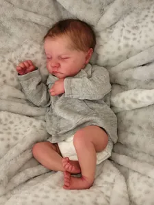 Close-up of sleeping Levi reborn baby doll showing realistic skin texture on plush blanket
