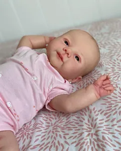 Close-up of lifelike 19-inch reborn doll face with pink outfit and bird pattern