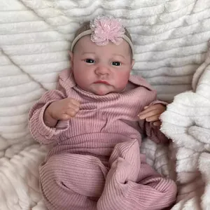 Lifelike Levi Reborn Doll in pink striped knit outfit and floral headband on plush blanket