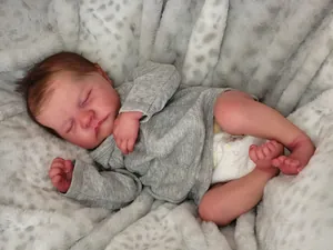 Close-up of 19-inch reborn doll with realistic brown hair and gray knitted sweater