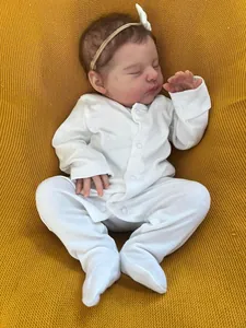 Detailed close-up of 19 inch reborn baby doll with white romper and headband on knit blanket