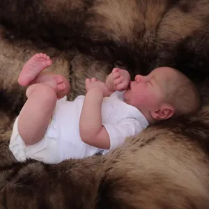 Realistische 19 Zoll Levi Reborn Puppe im weißen Strampler auf weichem braunem Kunstpelzbett