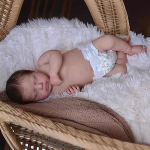 19-inch realistic reborn baby doll Loulou sleeping in a cozy woven cradle with soft blankets