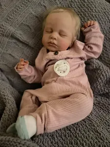 Close-up of sleeping reborn doll with realistic 3D skin texture and pink knit outfit