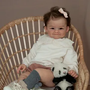 Realistic 60cm reborn baby doll with brown hair and panda toy in a wicker chair