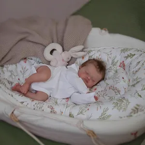 Lifelike 48cm reborn baby doll Rosalie in white onesie resting in floral baby nest