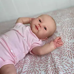 Realistic 19-inch Reborn Juliette baby doll in pink swan romper lying on floral bedding