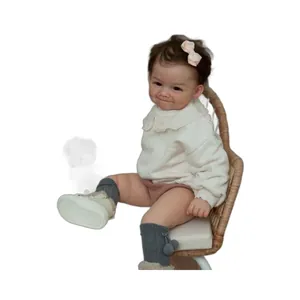 Realistic 60cm reborn baby doll with dimples and brown hair sitting on a wicker chair