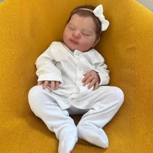 19-inch lifelike reborn baby doll in white romper sleeping on yellow knit background