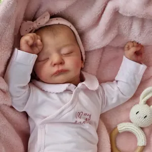 Gros plan d'une poupée Reborn de 19 pouces endormie en pyjama rose avec hochet